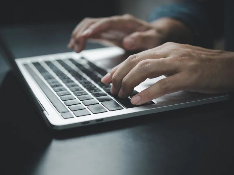 Primo Piano Delle Mani Di Una Persona Che Digita Su Una Tastiera Di Computer Portatile.