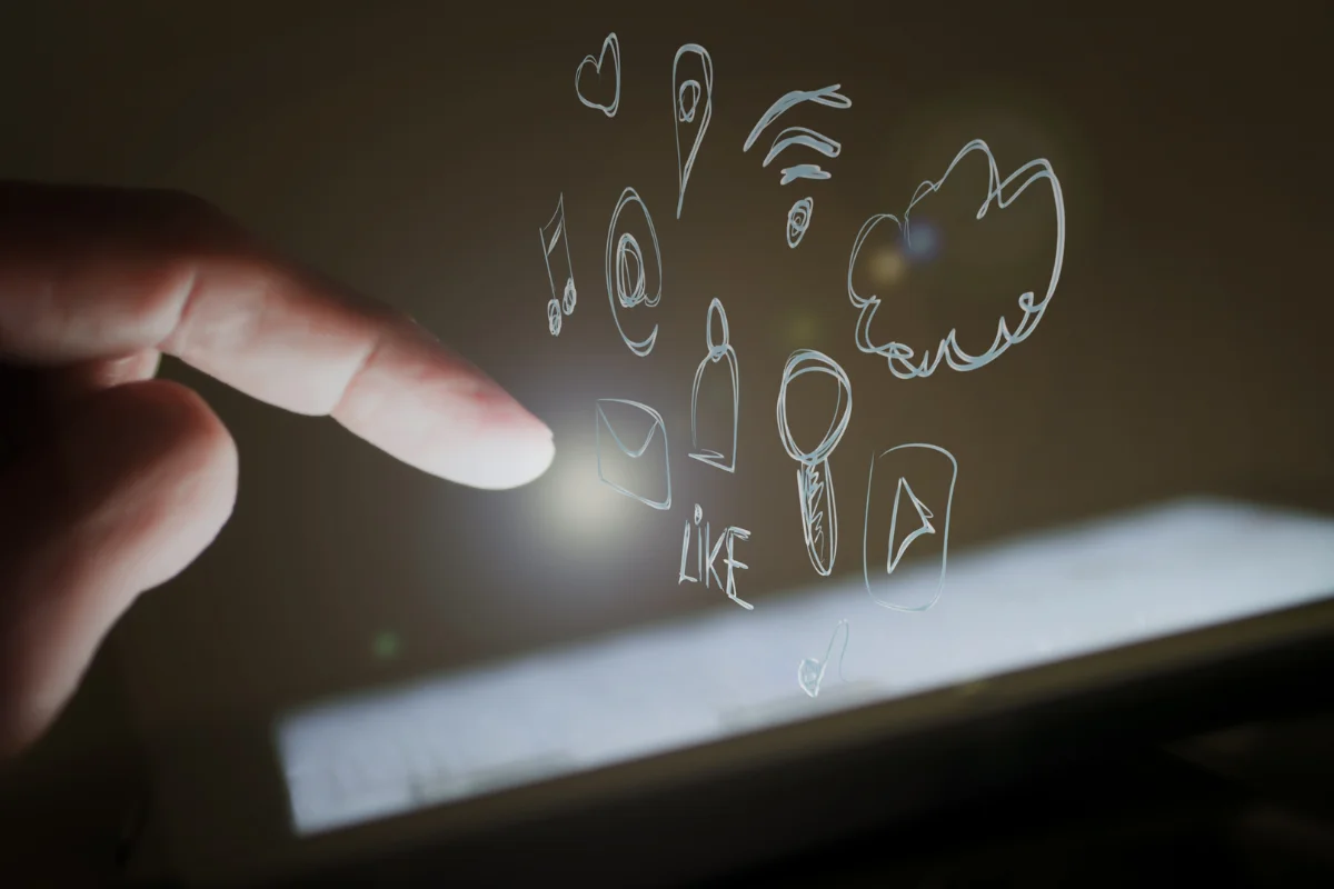 Dito tocca schermo di un tablet illuminato, circondato da icone di social media stilizzate.